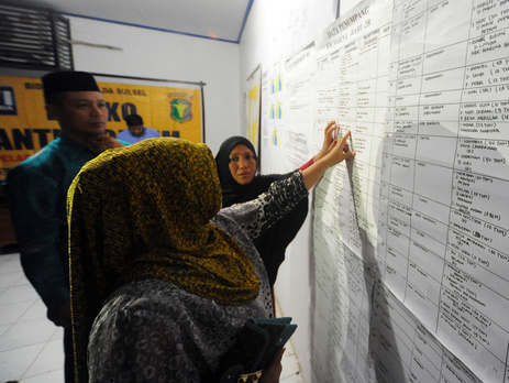 Родственники проверяют имена близких в списках погибших и пропавших в кризисном центре на острове Сулавеси