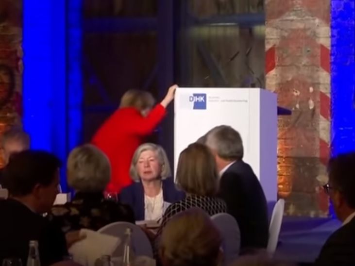 ﻿Меркель спіткнулася, піднімаючись на сцену. Відео