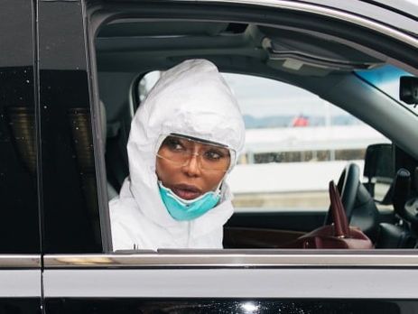 Кэмпбелл путешествует в защитном медицинском костюме, маске и резиновых перчатках