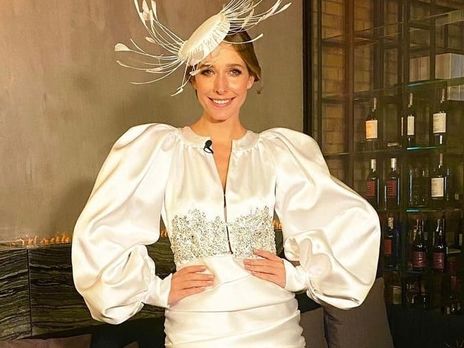 Осадча в червоному пальто позувала на капоті чорного автомобіля