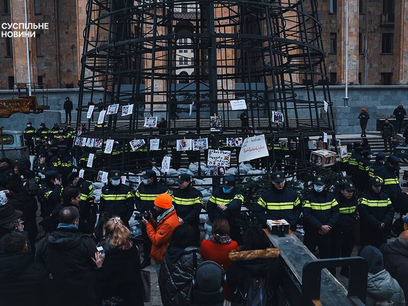 В Тбилиси начали охранять новогоднюю елку. Активисты развесили на ней фото избитых журналистов и митингующих