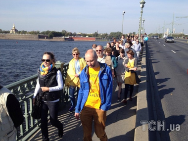 На Марш мира в Санкт-Петербурге вышли люди в сине-желтых одеждах с перечеркнутыми портретами Путина
